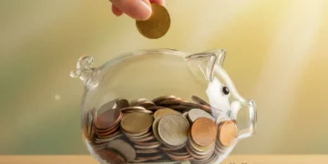 Hand putting coin into piggy bank, symbolizing saving money over 30 days.